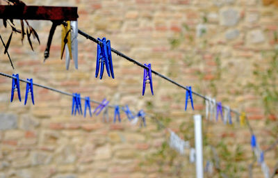 Multi colored clothespins hanging on rope against fence