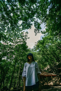 Full length of woman standing against trees in forest