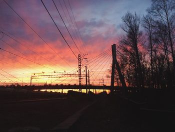 Silhouette electricity pylon against sky during sunset