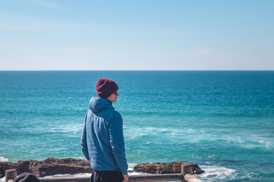 Rear view of woman looking at sea against clear sky