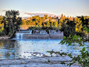 Scenic view of river by trees against sky