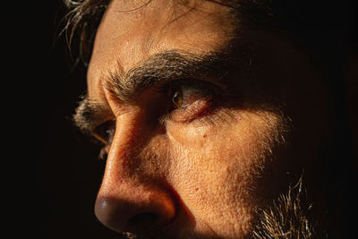 Man's face on black background behind a window with bars