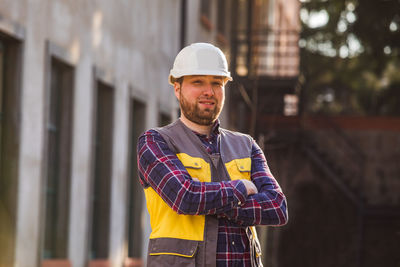 Young man wearing hat standing against built structure