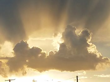 Low angle view of sunlight streaming through clouds