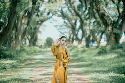 Young woman standing against trees