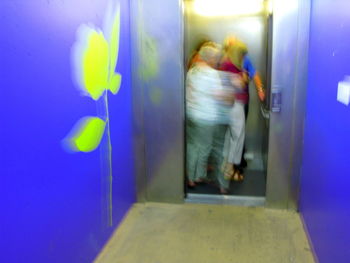 Blurred motion of woman walking in illuminated corridor