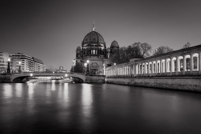 Illuminated river by berlin cathedral against clear sky during sunset