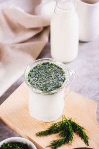 Glass with fresh turkish ayran with dill and greens on the table vertical view