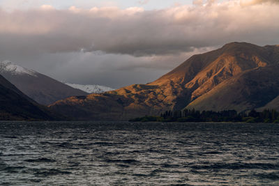 Scenic view of lake and mountains against dramatic sky