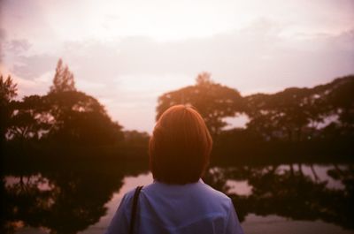 Rear view of man looking at lake against sky