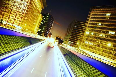 Light trails on road in city against sky at night