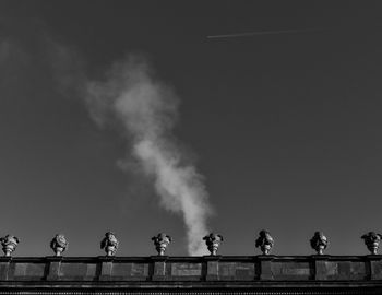 Low angle view of white smoke rises over a historic building.