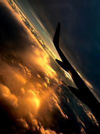 Low angle view of airplane flying in sky during sunset