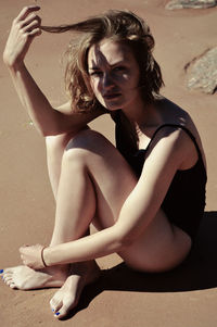 Full length of young woman sitting at beach