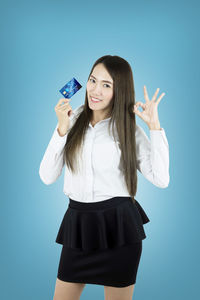 Portrait of smiling young woman against blue background