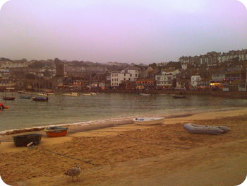 Boats moored in city against sky during sunset