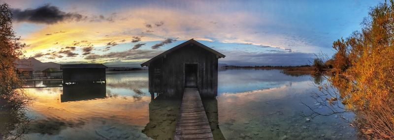 Panoramic view of lake and buildings against sky during sunset