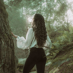 Rear view of woman standing in forest