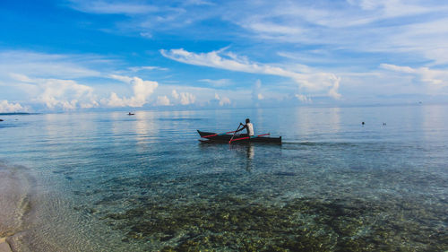 Scenic view of sea against sky and a fisherman rowing his boat from the shore to the sea