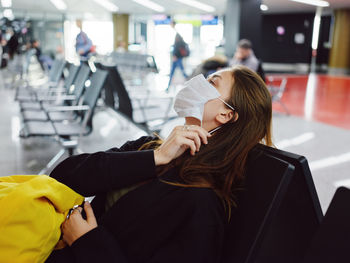 Rear view of woman sitting at airport