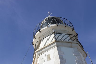 Low angle view of lighthouse against building against clear blue sky