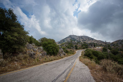Road leading towards mountains against sky