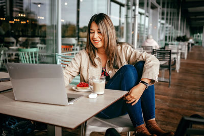 Mexican woman chats with friends, enjoys morning coffee on cafe terrace. digital life, slow living