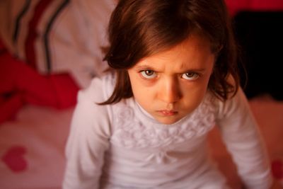 High angle view of girl sitting on bed at home