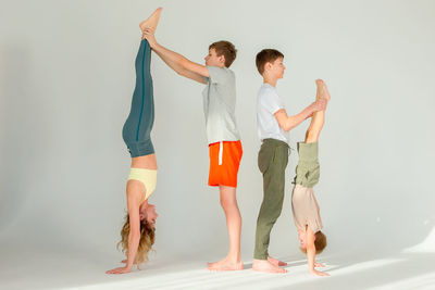 A sports family, a slender woman, a boy and two teenagers stand on their hands
