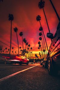 Cars on road against sky during sunset