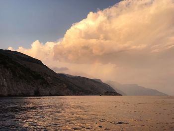 Scenic view of sea by mountains against sky