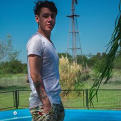 Side view portrait of young man standing against clear blue sky