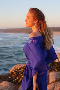 Young woman standing at beach during sunset