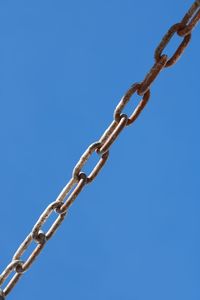 Low angle view of chain against clear blue sky