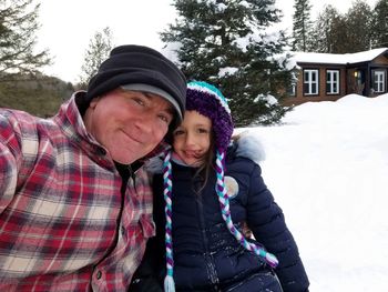 Portrait of smiling father and daughter on snow covered land during winter