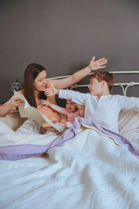 Close-up of mother telling bed time story to children on bed at home