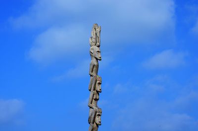 Low angle view of cross sculpture against blue sky