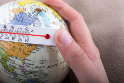 Close-up of hand with thermometer and globe