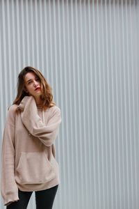 Portrait of beautiful young woman standing against wall