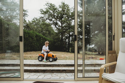 View through doors of boy on toy tractor