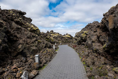 Footpath amidst rocks against sky