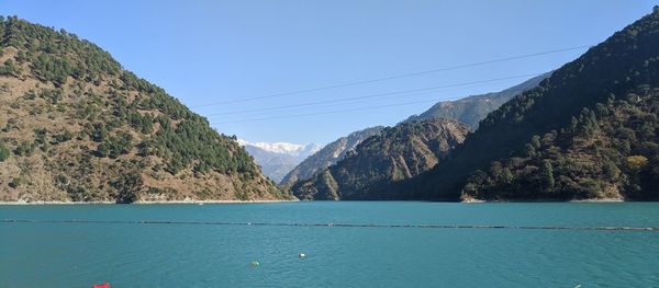 Scenic view of sea and mountains against clear blue sky