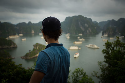 Rear view of man looking at lake against sky