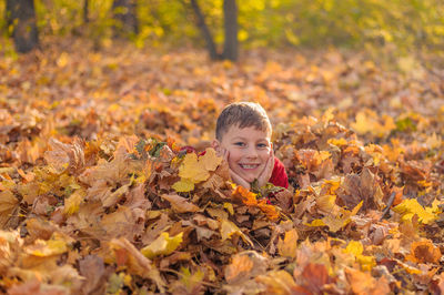 Portrait of smiling boy on leaves during autumn