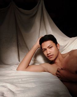 Portrait of young man lying in bed