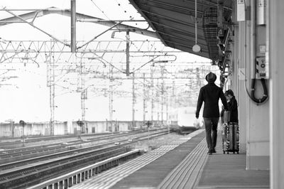 Rear view of people walking on railroad tracks