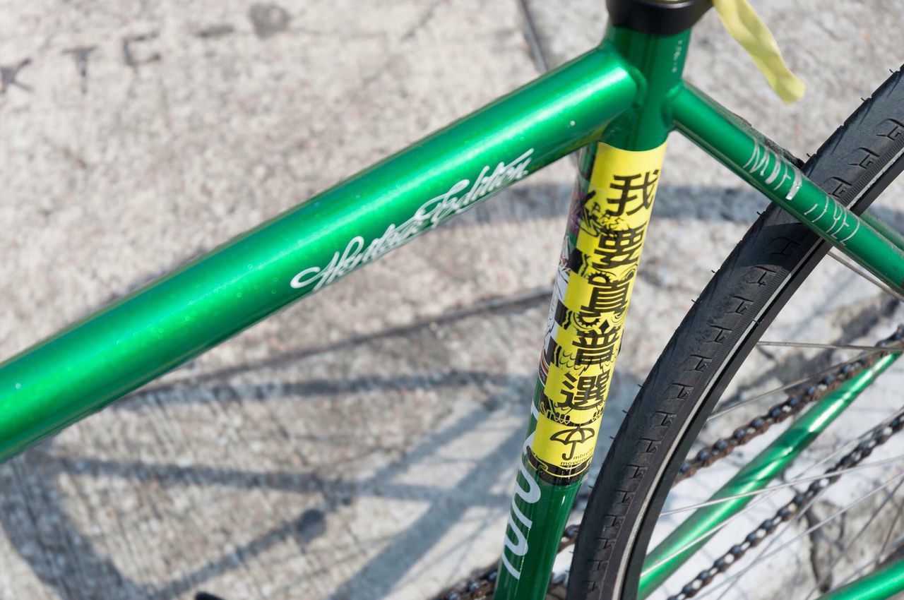 transportation, metal, close-up, high angle view, mode of transport, land vehicle, multi colored, yellow, street, metallic, blue, bicycle, no people, outdoors, day, part of, road, wheel, wall - building feature, stationary