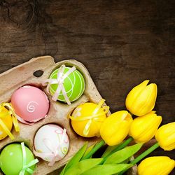 Directly above shot of yellow tulips by easter eggs on table