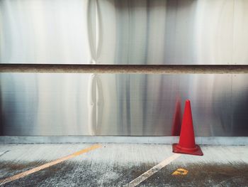 Red traffic cone by metal on road