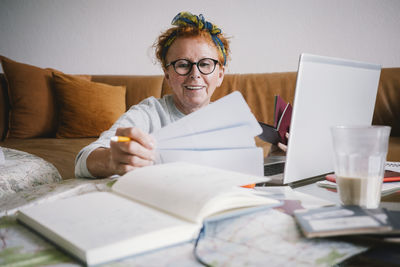 Happy senior woman holding tickets while planning trip